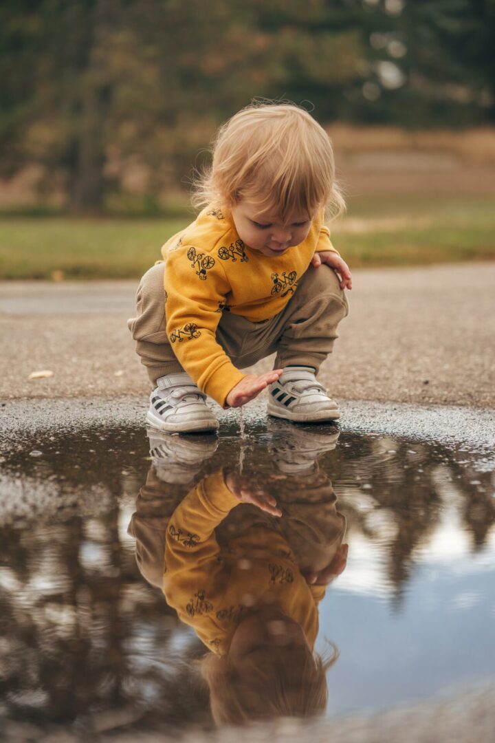 A toddler playing with water on the street