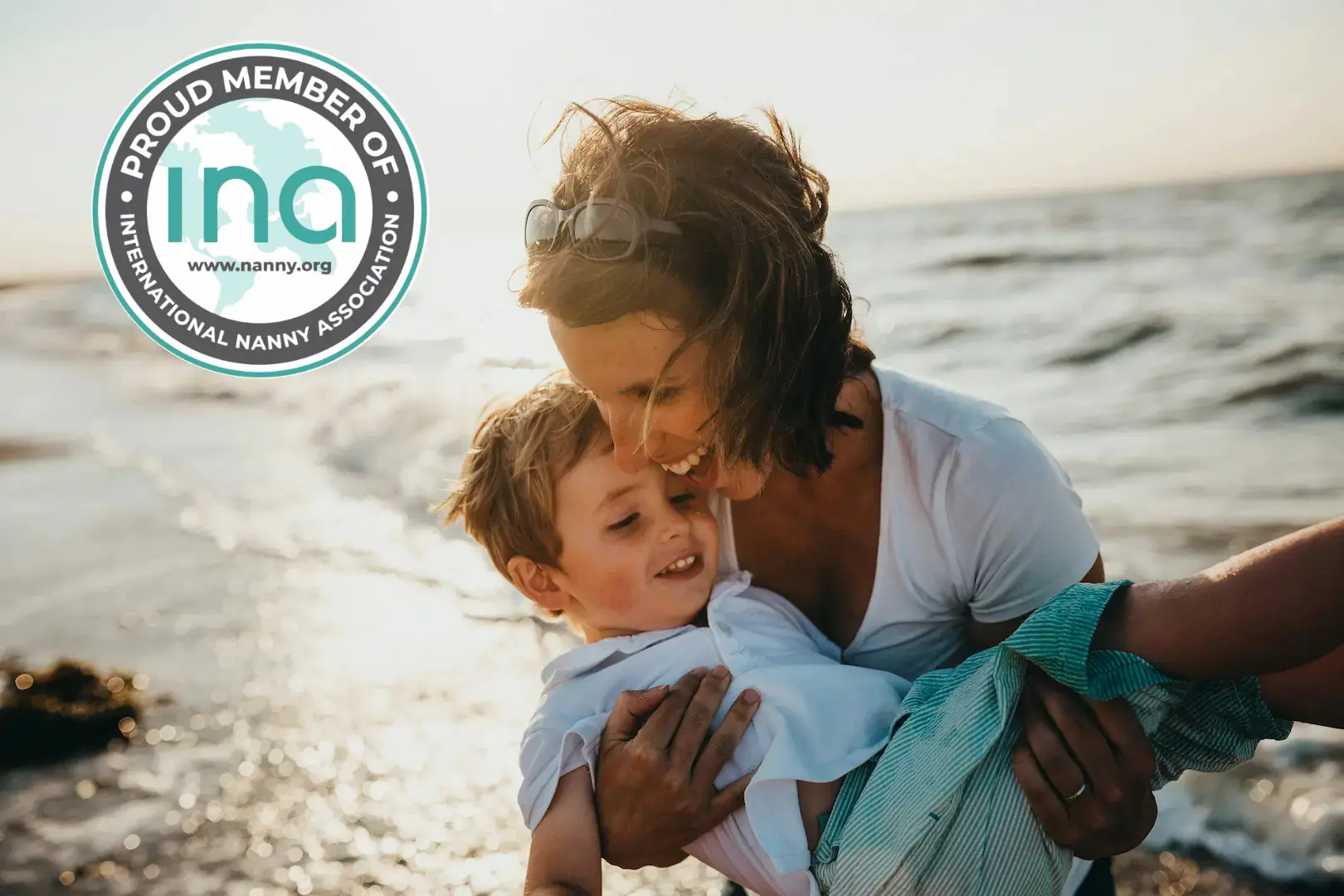 woman holding boy and laughing playing at the beach by the ocean